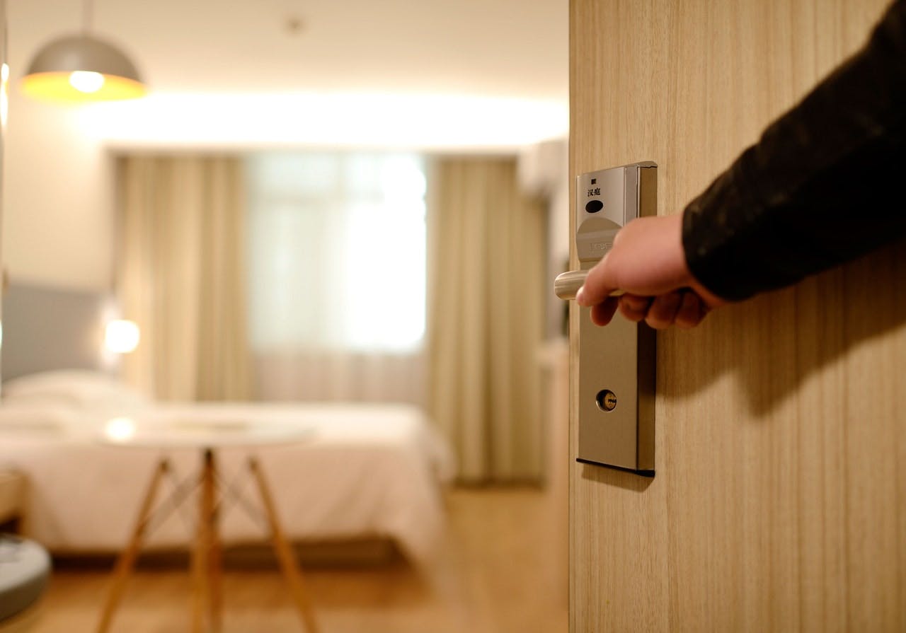 Person's arm opening a hotel room door