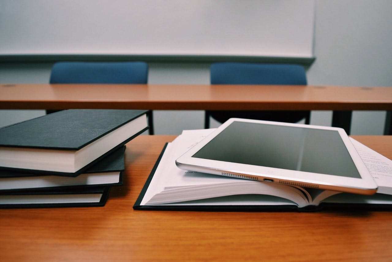Books and tablet on a desk in a classroom